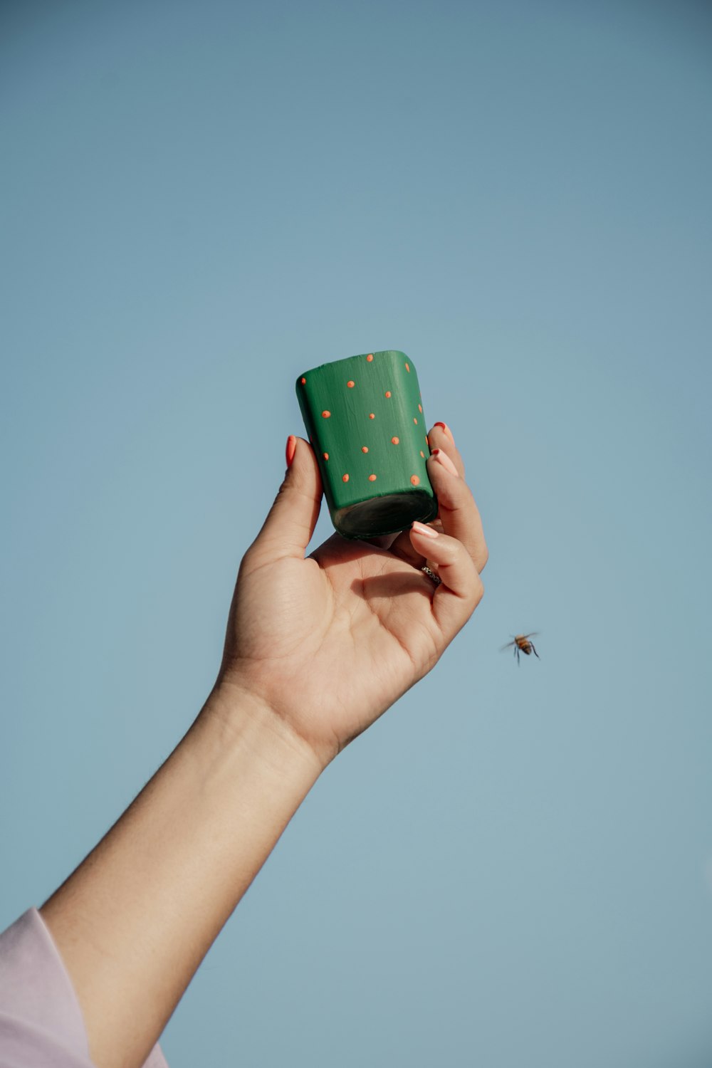 a hand holding a green cup with gold dots