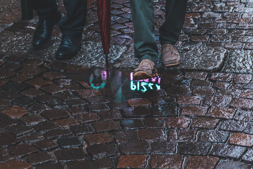 a person standing on a brick road with their feet on a skateboard