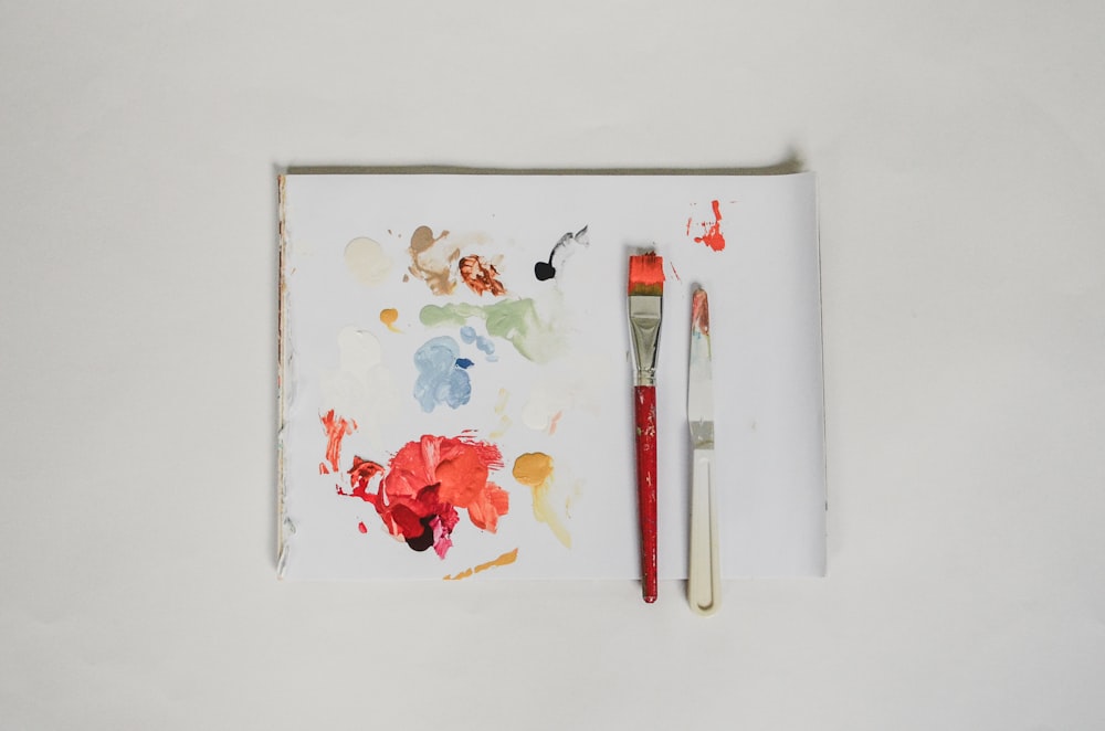 two paintbrushes are sitting on a piece of paper