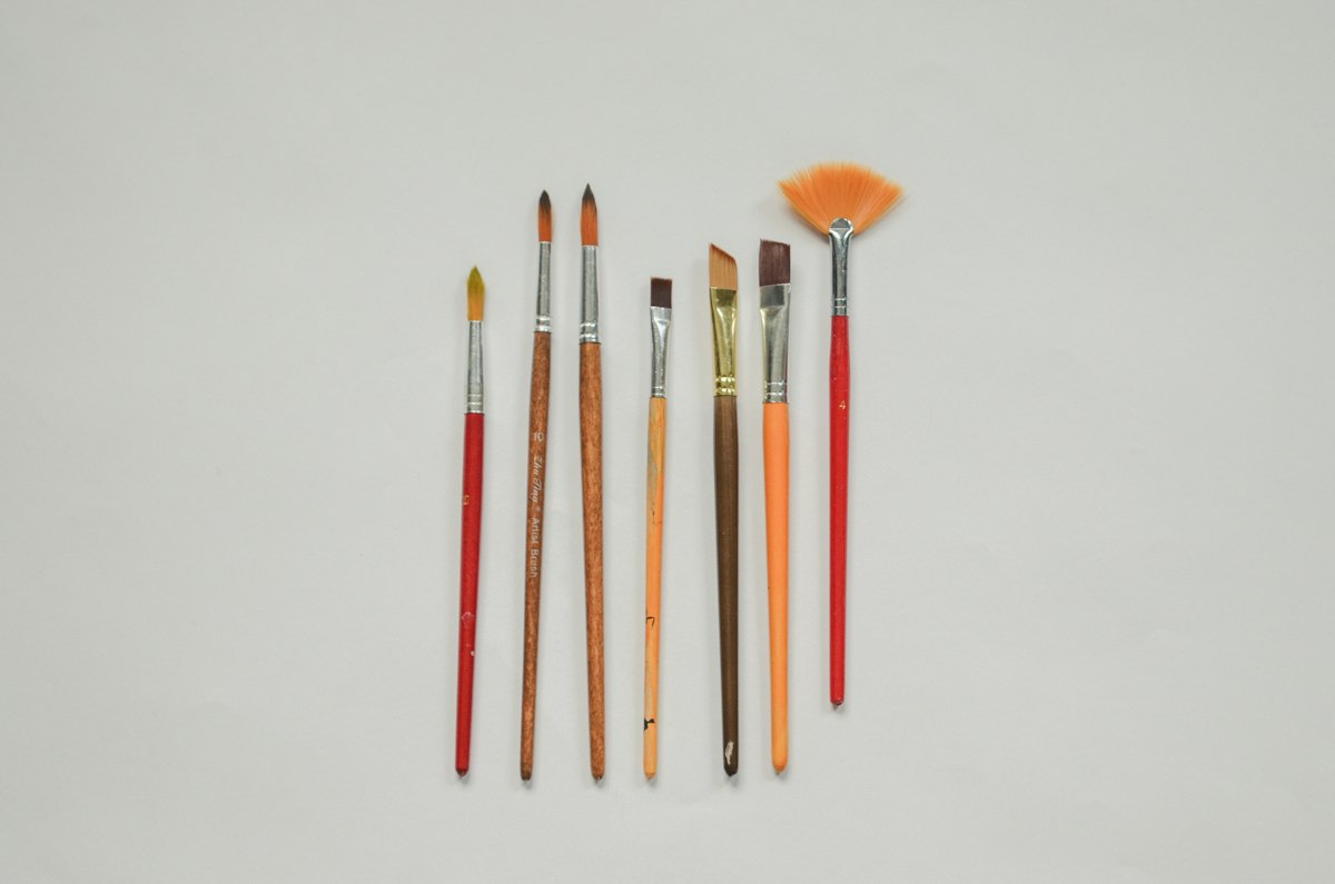 Several paint brushes of different sizes laid out side by side for comparison