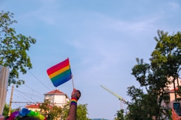 Close-up of a softball glove holding a ball painted with the rainbow pride flag.