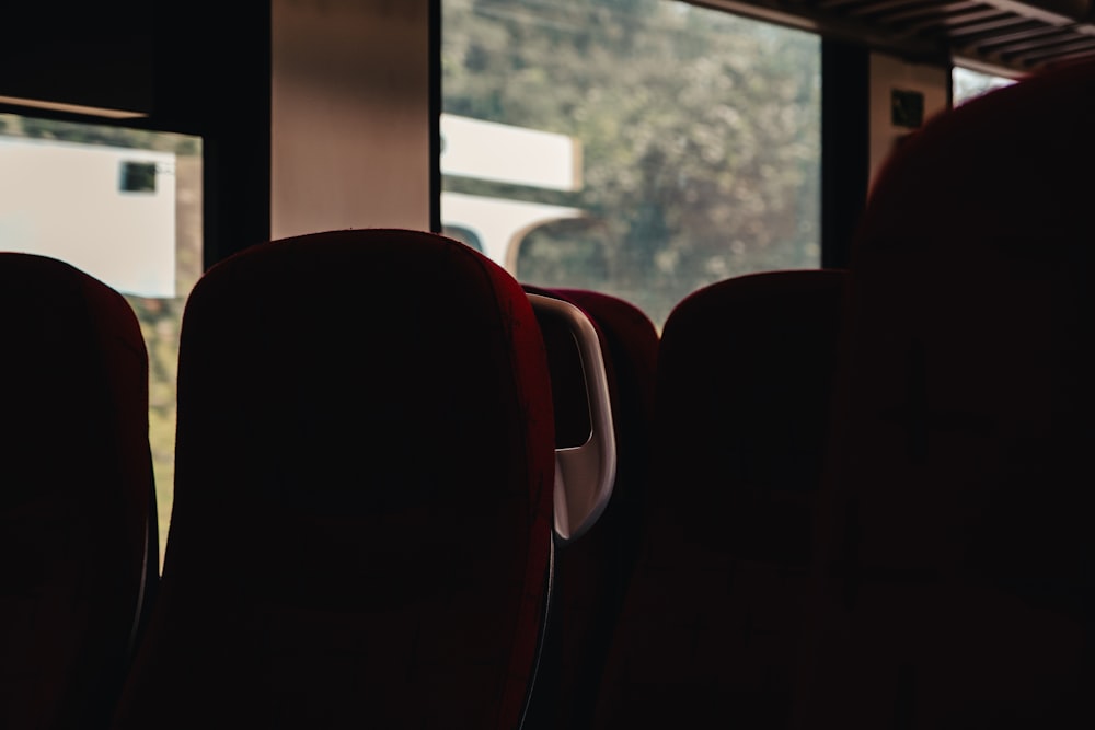 eine Reihe roter Sitze, die neben einem Fenster sitzen