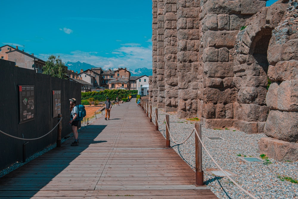 a wooden walkway between two stone buildings