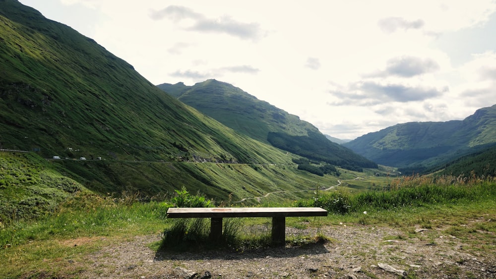 a wooden bench sitting on top of a lush green hillside