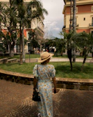 A model wearing a chic summer dress walking through a sunlit park.