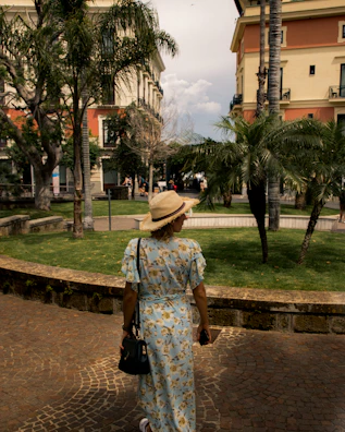 A model wearing a chic summer dress walking through a sunlit park.