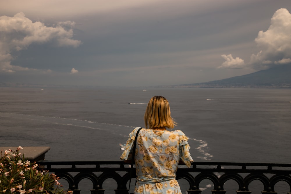 a woman standing on a balcony looking out at the ocean