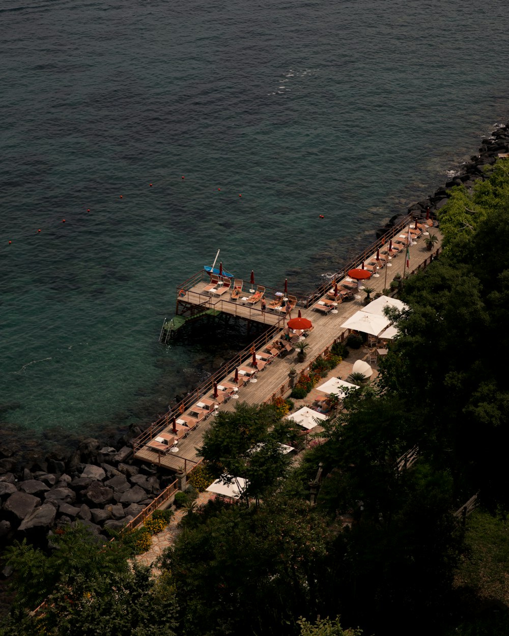 an aerial view of a pier with chairs and umbrellas