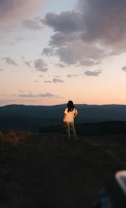 a woman standing on top of a lush green hillside