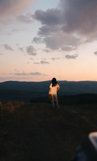a woman standing on top of a lush green hillside