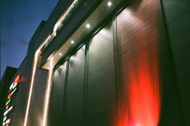 A commercial building exterior brightly lit by powerful flood lights at dusk