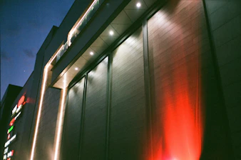 A commercial building exterior brightly lit by powerful flood lights at dusk