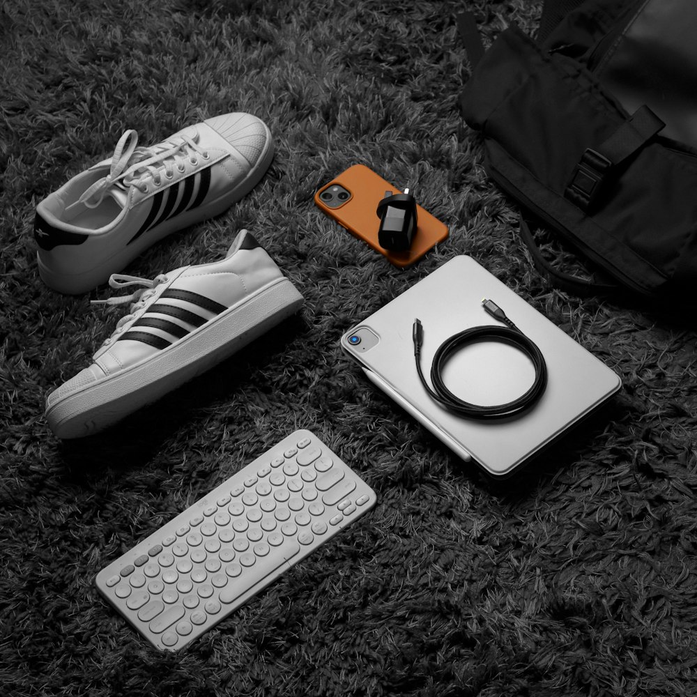 a black and white photo of a laptop, keyboard, headphones, and a