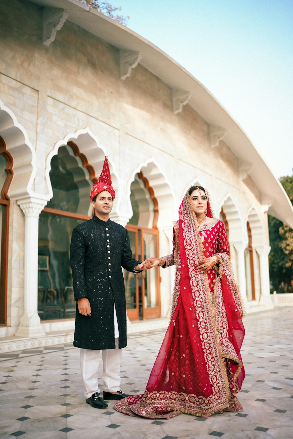 a man and woman in indian garb standing in front of a building