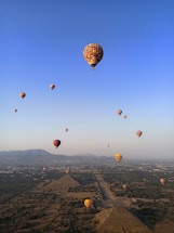 A colorful hot air balloon soaring over the ancient pyramids of Teotihuacán at sunrise