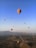 A colorful hot air balloon rising over the ancient pyramids of Teotihuacán at sunrise.