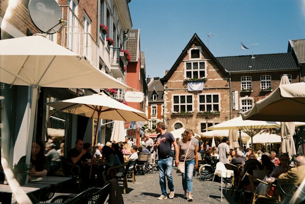 A group of people sitting at tables outside of a building — Aachen, Germany