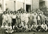A black-and-white throwback photo of the school’s very first graduating class posing proudly outside the entrance.