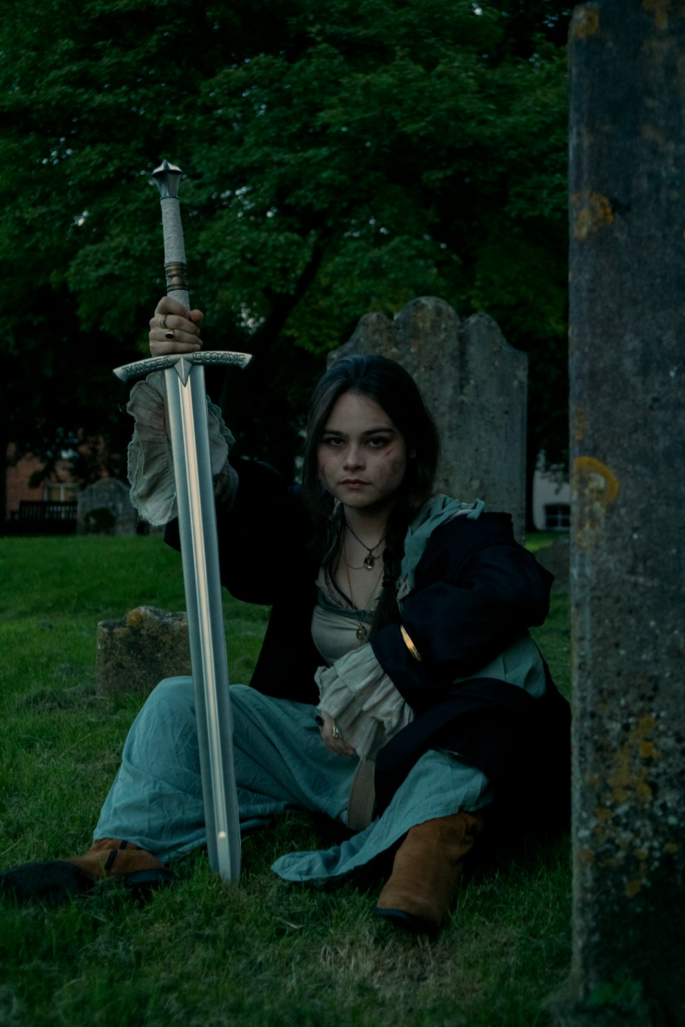 a woman sitting on the ground holding a sword