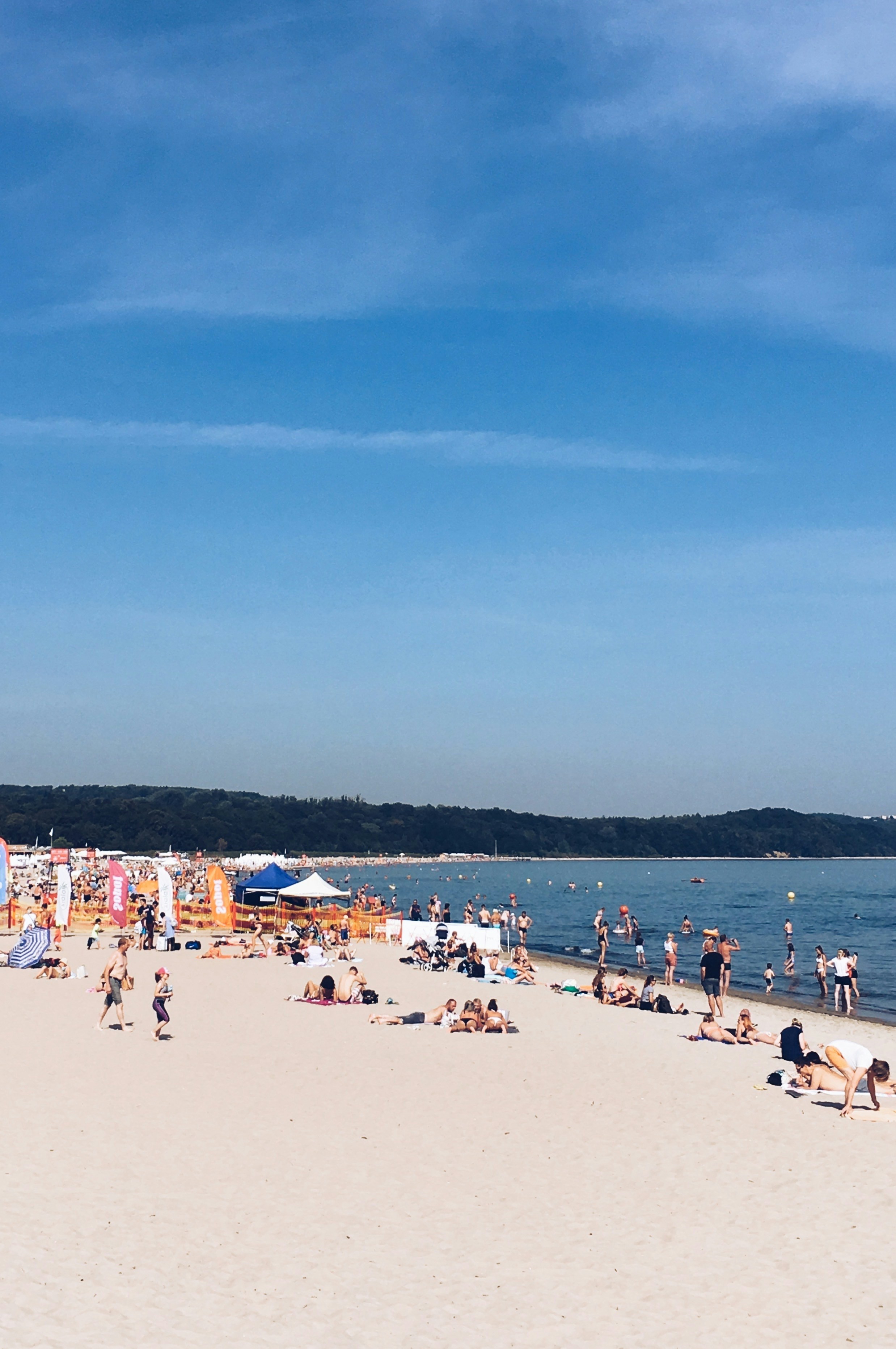 a crowded beach with people and umbrellas on a sunny day