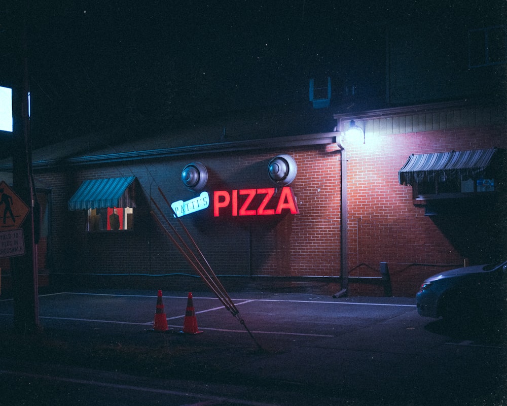 a pizza restaurant with a neon sign on the side of the building