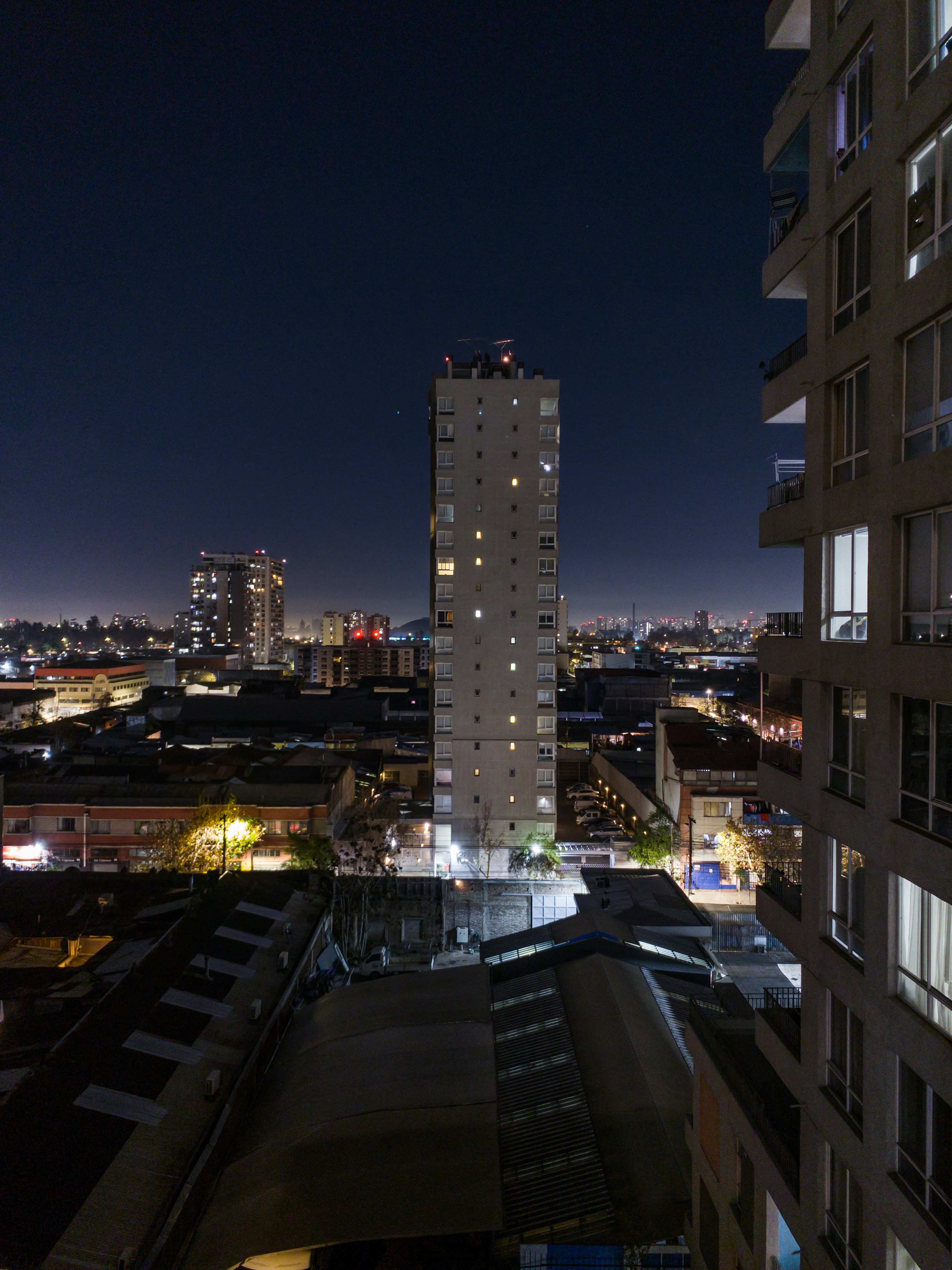 Urban city skyline at night with glowing hotel windows and street life below