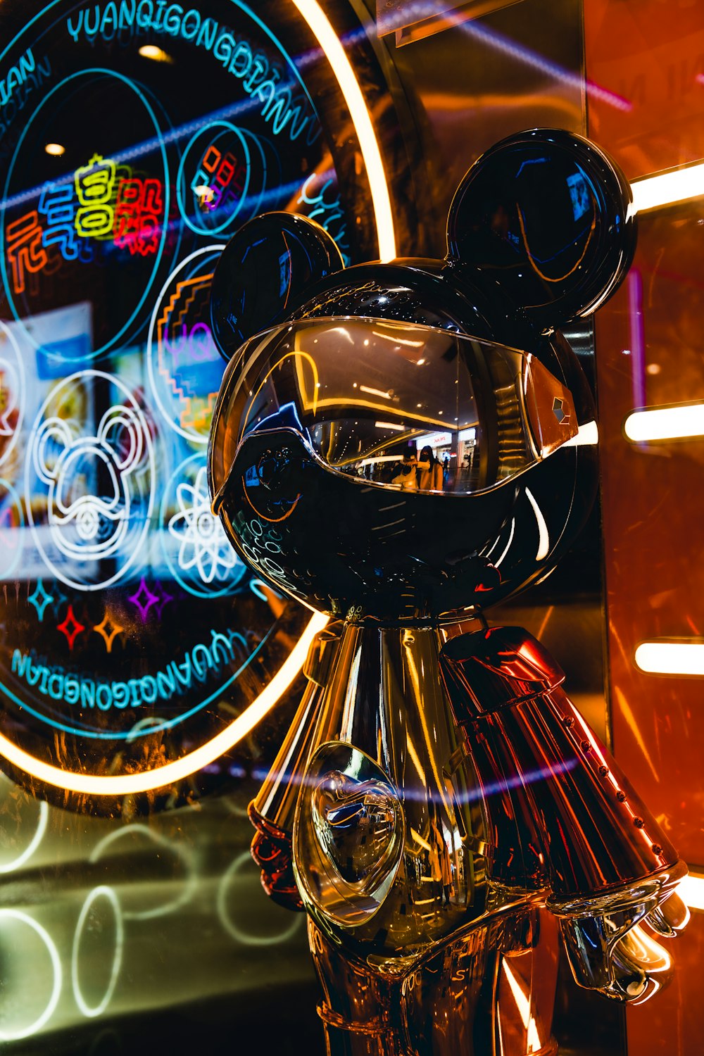 a mickey mouse statue in front of a neon sign