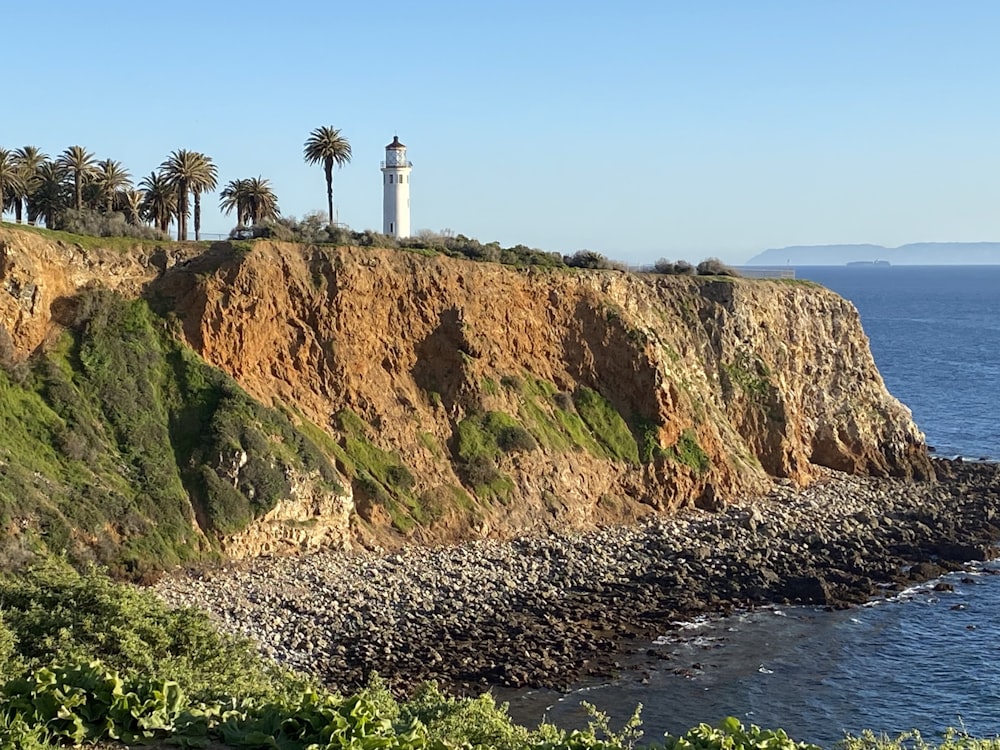 a lighthouse on top of a cliff next to the ocean
