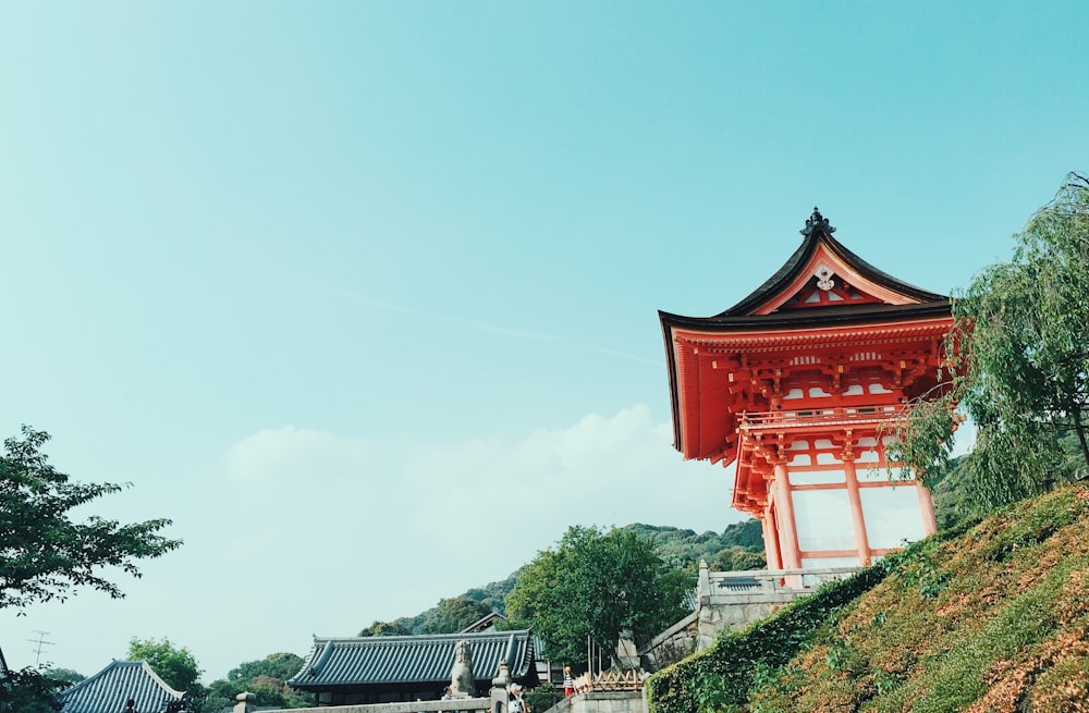 a tall red pagoda sitting on top of a lush green hillside