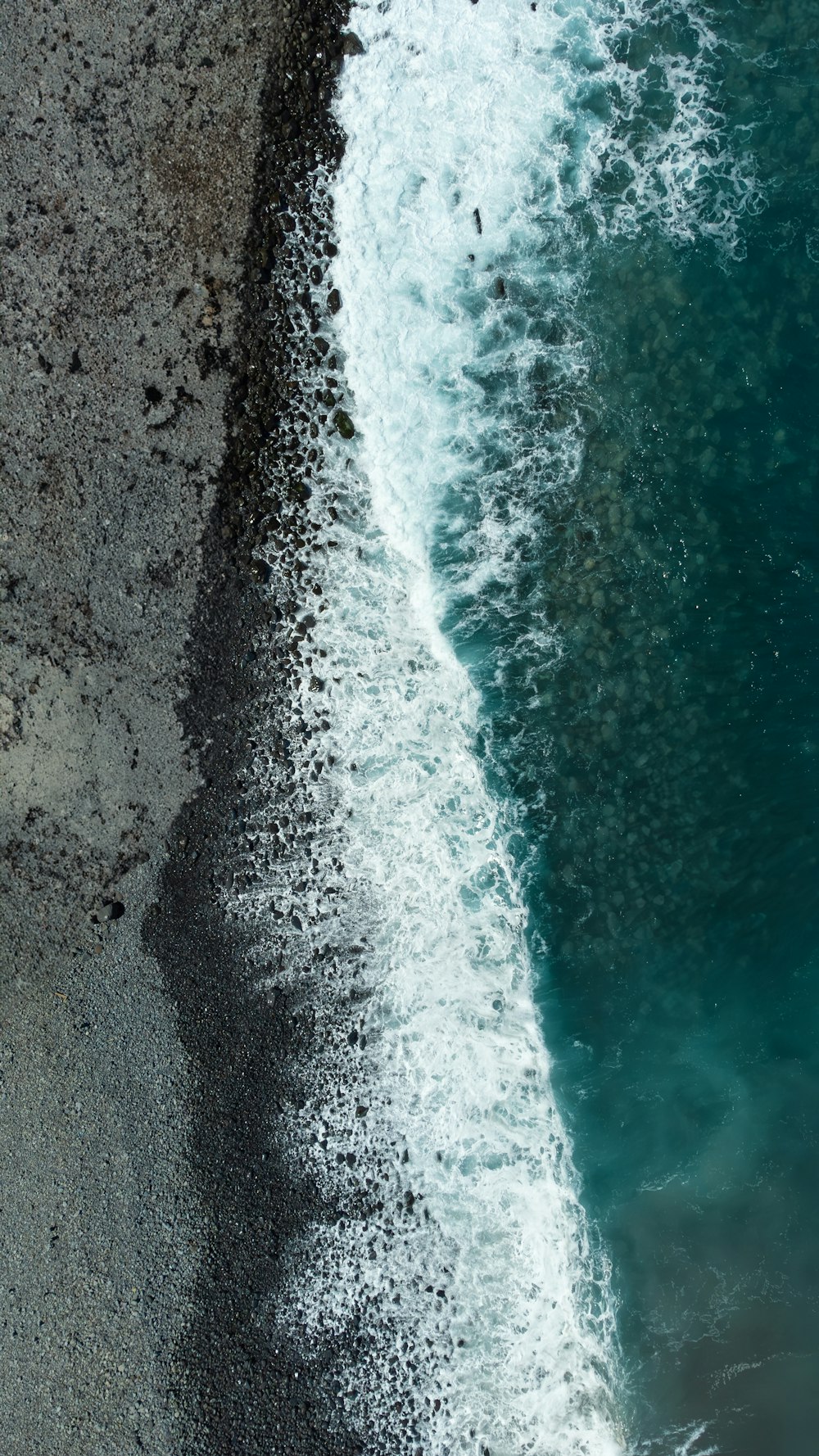 an aerial view of a beach with a wave coming in