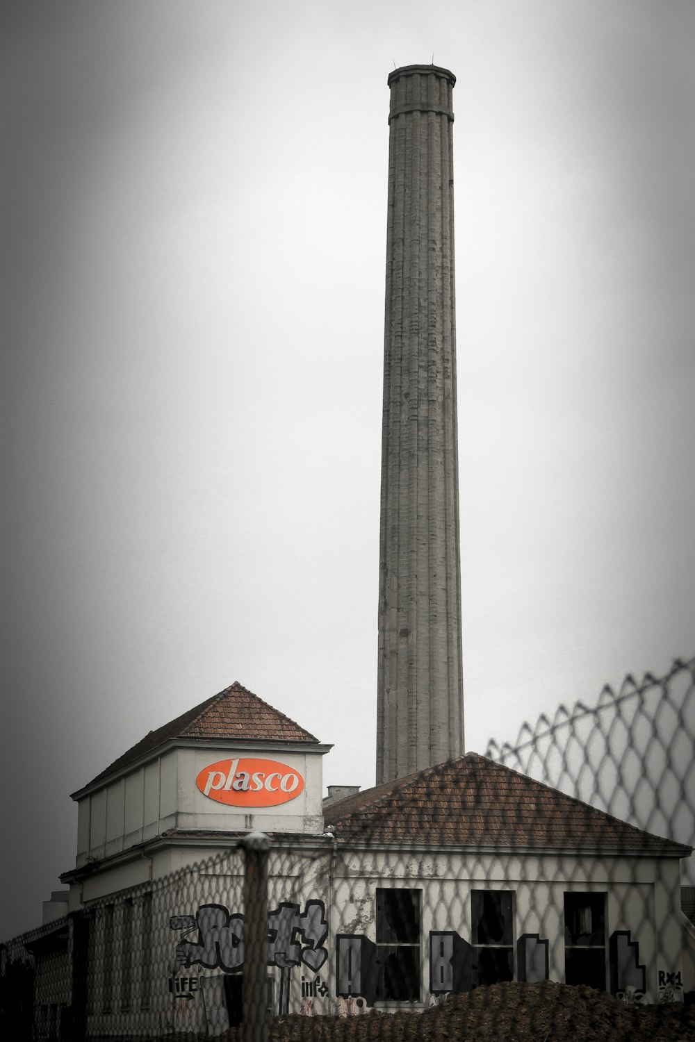 a building with a tall chimney next to a fence
