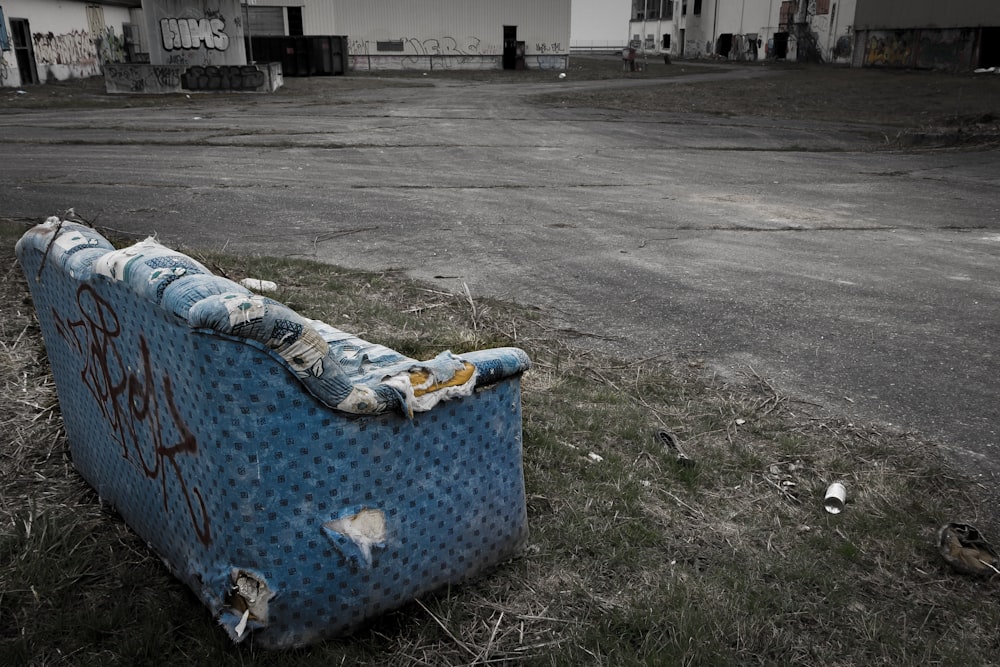 a blue couch sitting on top of a grass covered field