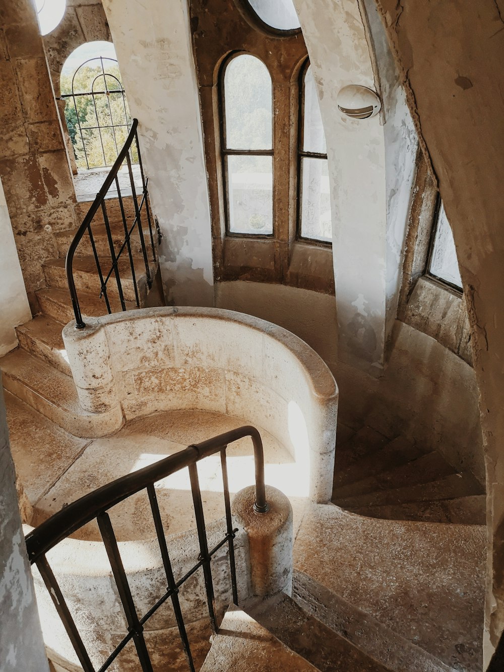a spiral staircase in a stone building with arched windows
