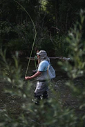 a man standing in a river holding a fish