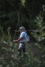 a man standing in a river holding a fish