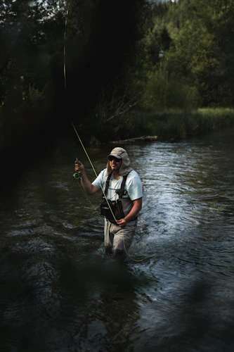 An angler working a flat tailwater run with a single dry fly, the water type where a dubbed cinnamon ant shines