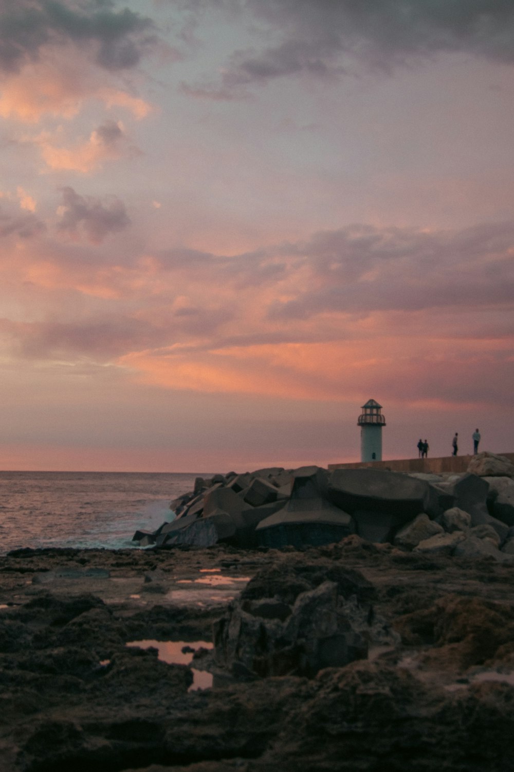 a couple of people standing on top of a rocky beach