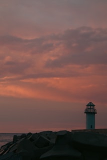 A serene lighthouse standing tall against a sunset sky.