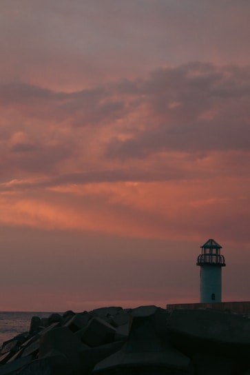 A serene lighthouse standing tall against a sunset sky.