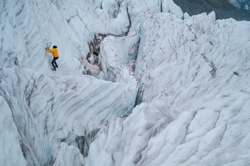 a man climbing up the side of a snow covered mountain