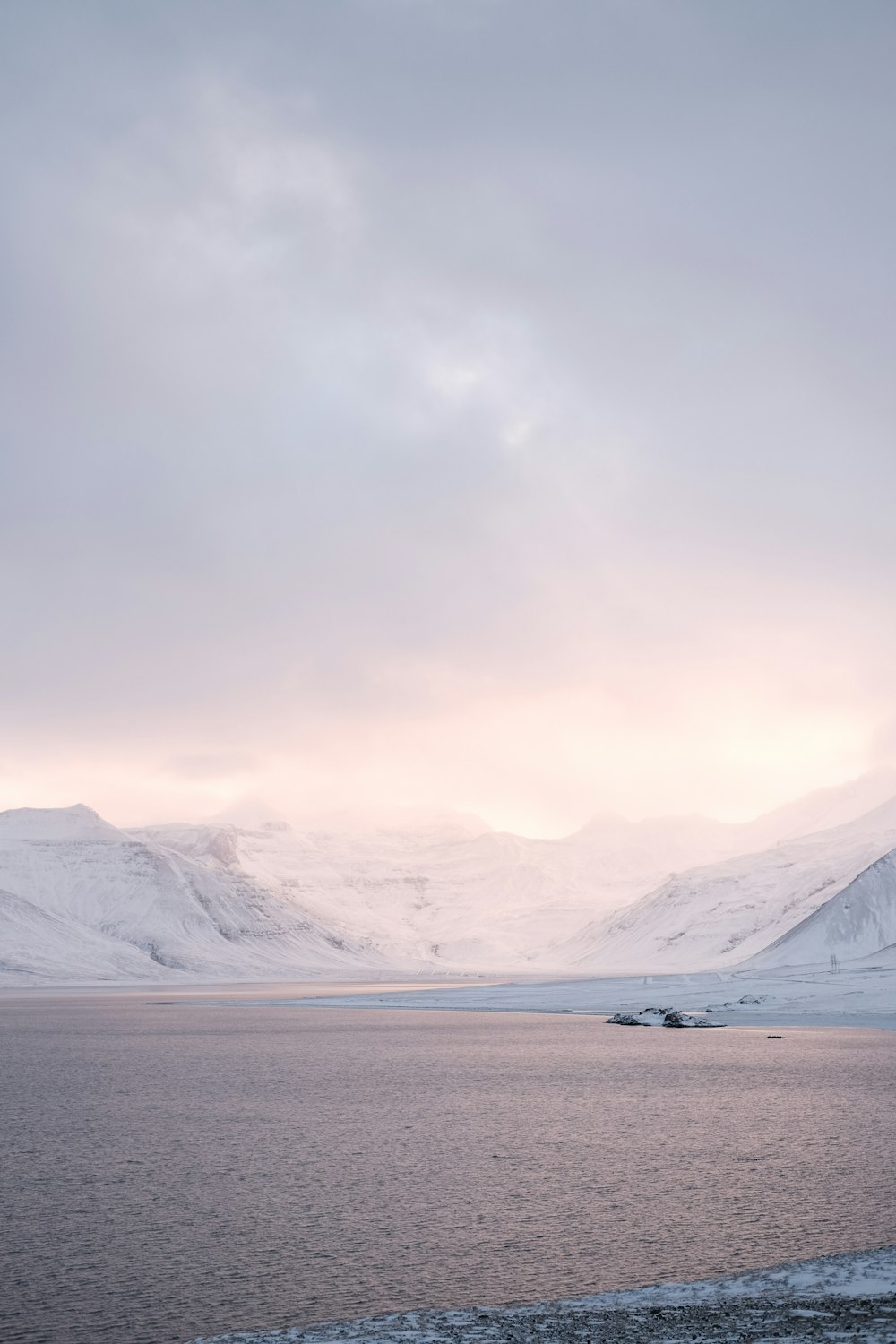 a large body of water surrounded by snow covered mountains