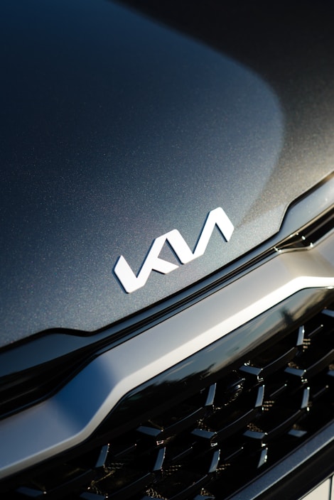 Close-up of a shiny car grille with the Baltic Korean Auto logo reflected.