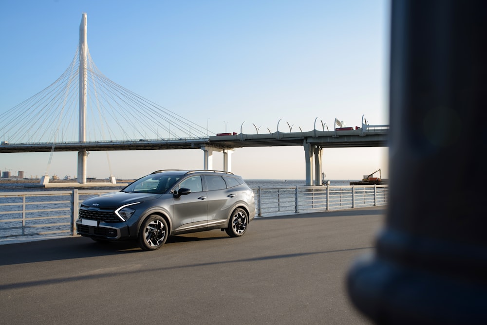 a silver car driving down a street next to a bridge