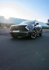 A sleek luxury SUV parked in front of a modern office building at sunset.