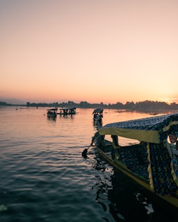 A peaceful lakeside scene with traditional boats near Swosti Chilika Resort at dawn.