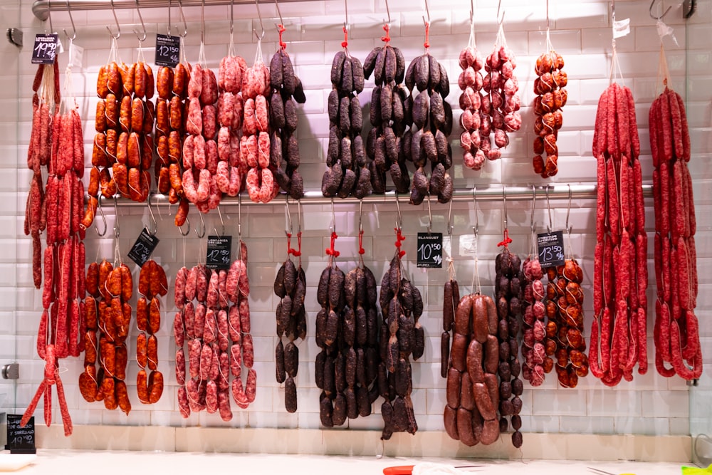 a bunch of sausage hanging from hooks in a kitchen