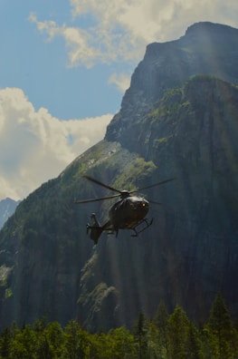 a helicopter flying in the air over a mountain