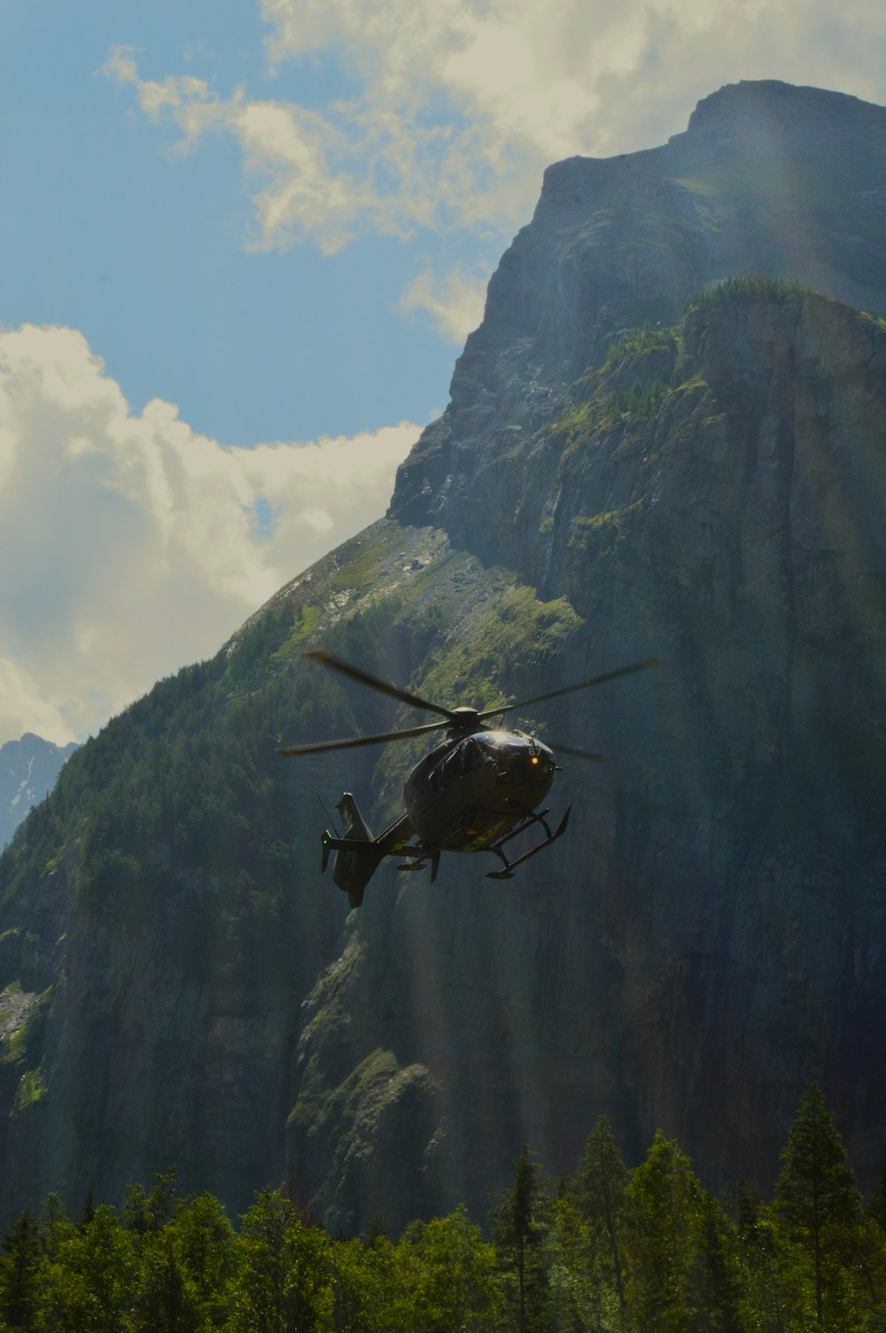 a helicopter flying in the air over a mountain