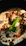 Close-up of a gourmet dip with meat and fresh vegetables on a rustic wooden table.