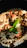 Close-up of a gourmet dip with meat and fresh vegetables on a rustic wooden table.